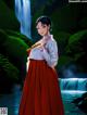 A woman in a red skirt standing in front of a waterfall.