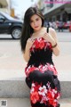 A woman in a red and black dress sitting on a ledge.