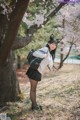 A woman in a school uniform standing next to a tree.