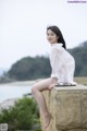 A woman sitting on top of a stone wall next to the ocean.