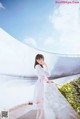 A woman in a white dress standing on a balcony.