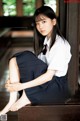 A young woman in a school uniform sitting on a bench.