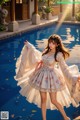 A woman in a white dress standing next to a pool.