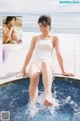 A woman in a white bathing suit sitting in a pool.