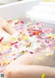 A woman laying in a bathtub filled with flowers.