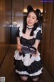 A woman in a black and white maid outfit holding a pair of shoes.