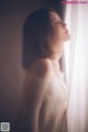 A woman in a white dress looking out a window.