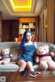 A woman sitting on a couch with two teddy bears.