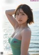 A woman in a green bathing suit standing on a beach.