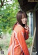 A woman in an orange kimono standing in front of a building.